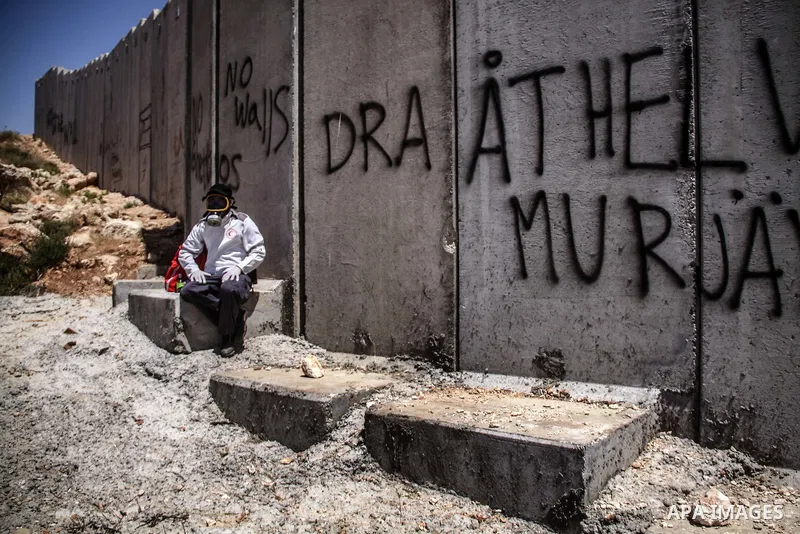 Palestinian protester sits under Israeli's separation barrier during a weekly demonstration in the West Bank village if Nilin on June 8, 2012. When completed, 85 percent of the wall will have been built inside the West B...