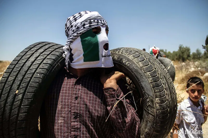 Palestinian protester burns tires during a weekly demonstration against Israel's controversial separation barrier in the West Bank village of Nilin on June 8, 2012. When completed, 85 percent of the wall will have been b...