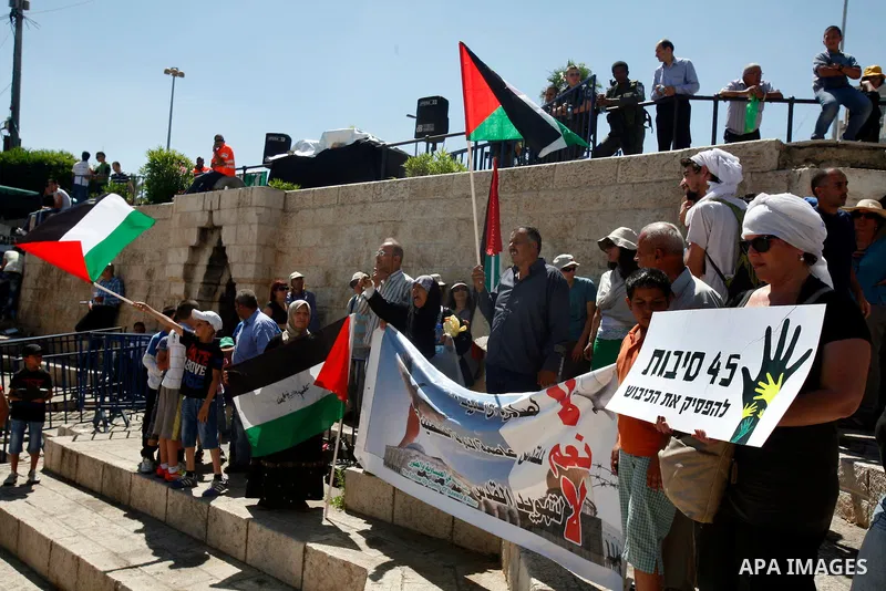Palestinians hold national flag and shout slogans during a protest against continuing of 'Judaization of Jerusalem' by Jewish settlers and confiscating Palestinian lands at Damascus gate after Friday prayer in east jerus...