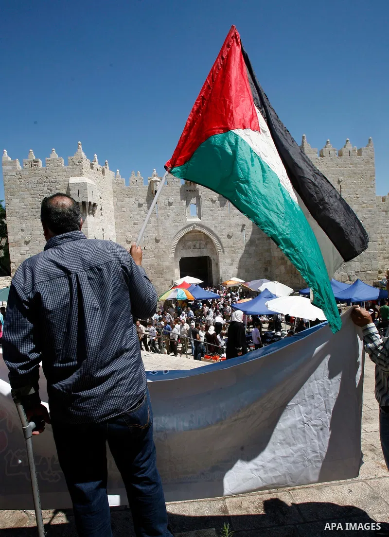 Palestinians hold national flag and shout slogans during a protest against continuing of 'Judaization of Jerusalem' by Jewish settlers and confiscating Palestinian lands at Damascus gate after Friday prayer in east jerus...