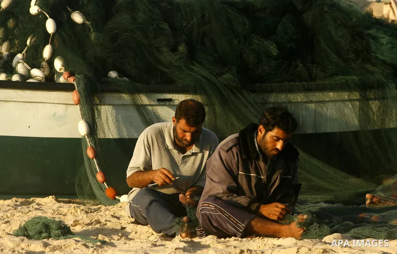 Palestinians fishermen repair their nets at the beach of Rafah city on June 10, 2012 Fishermen, suffer from the tightening of the Israeli siege imposed on Palestinian fishermen a forbidden fishermen by Israel to enter th...
