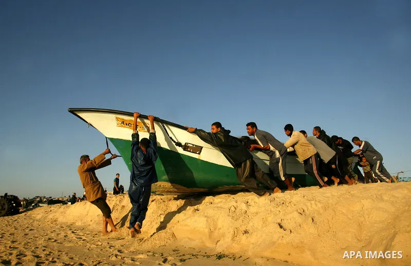 Palestinian fishermen pull their boat at the beach of Rafah city June 10, 2012. Fishermen, suffer from the tightening of the Israeli siege imposed on Palestinian fishermen a forbidden fishermen by Israel to enter the sea...