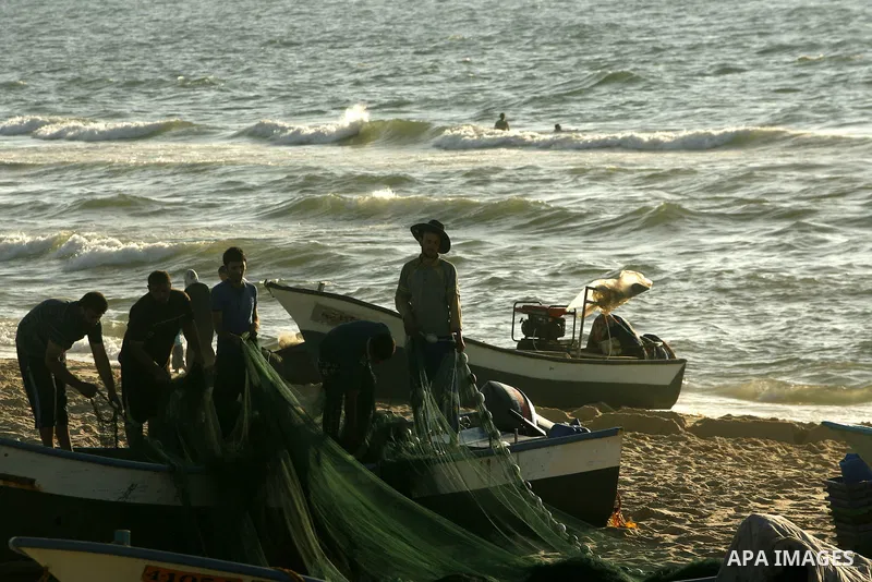 Palestinian fishermen repair their nets at the beach of Rafah city on June 10, 2012 Fishermen, suffer from the tightening of the Israeli siege imposed on Palestinian fishermen a forbidden fishermen by Israel to enter the...