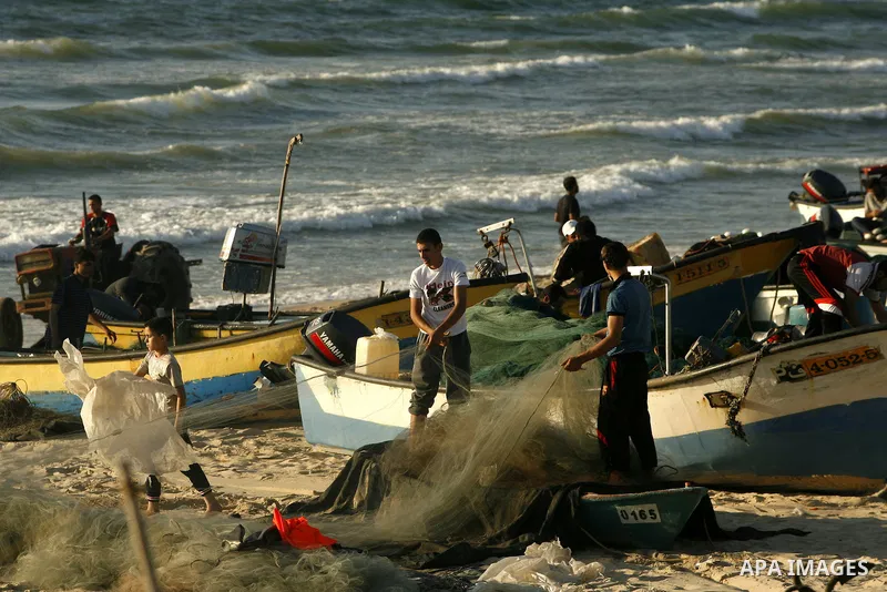 Palestinian fishermen repair their nets at the beach of Rafah city on June 10, 2012 Fishermen, suffer from the tightening of the Israeli siege imposed on Palestinian fishermen a forbidden fishermen by Israel to enter the...