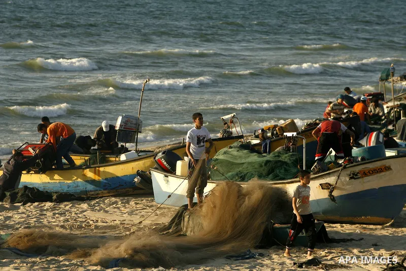 Palestinian fishermen repair their nets at the beach of Rafah city on June 10, 2012 Fishermen, suffer from the tightening of the Israeli siege imposed on Palestinian fishermen a forbidden fishermen by Israel to enter the...