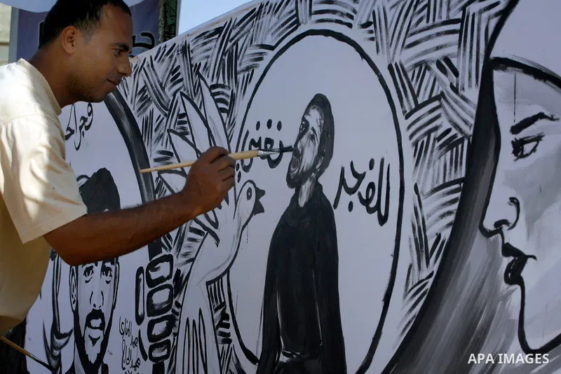 A Palestinian paints a mural depicting prisoners Mahmoud Al-Sarsak and Akram Al-Rekhawi in Rafah, in the southern Gaza Strip June 10, 2012. Al-Sarsak and al-Rekhawi, two Palestinian prisoners held in Israeli jails, have...