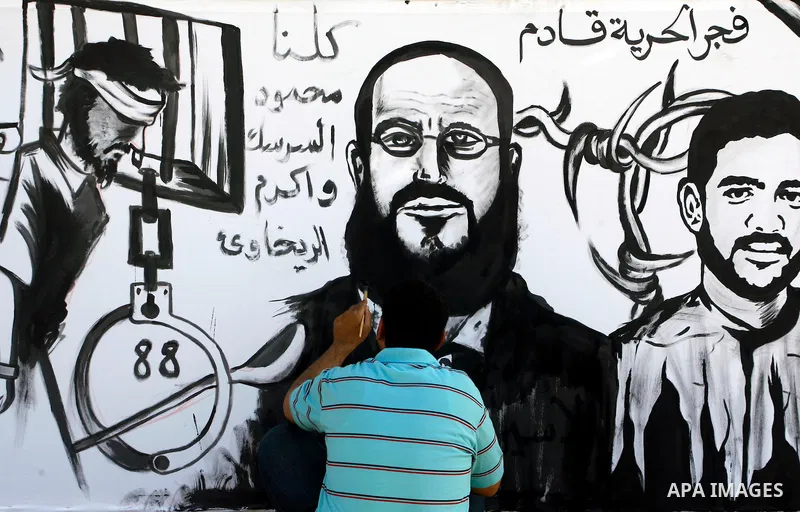 A Palestinian paints a mural depicting prisoners Mahmoud Al-Sarsak and Akram Al-Rekhawi in Rafah, in the southern Gaza Strip June 10, 2012. Al-Sarsak and al-Rekhawi, two Palestinian prisoners held in Israeli jails, have...