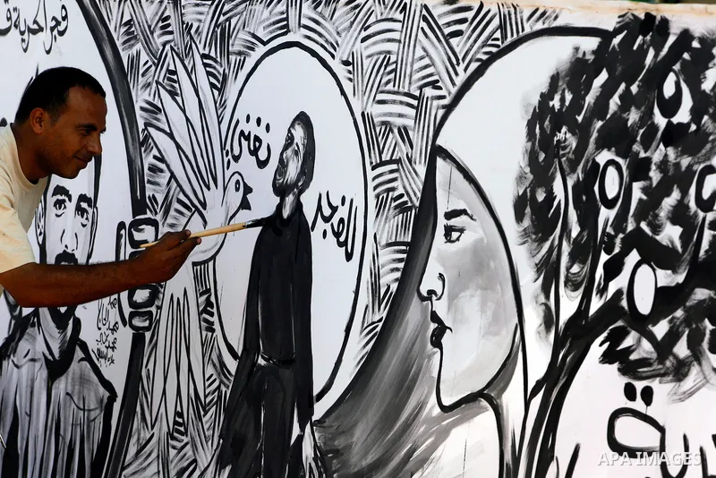 A Palestinian paints a mural depicting prisoners Mahmoud Al-Sarsak and Akram Al-Rekhawi in Rafah, in the southern Gaza Strip June 10, 2012. Al-Sarsak and al-Rekhawi, two Palestinian prisoners held in Israeli jails, have...
