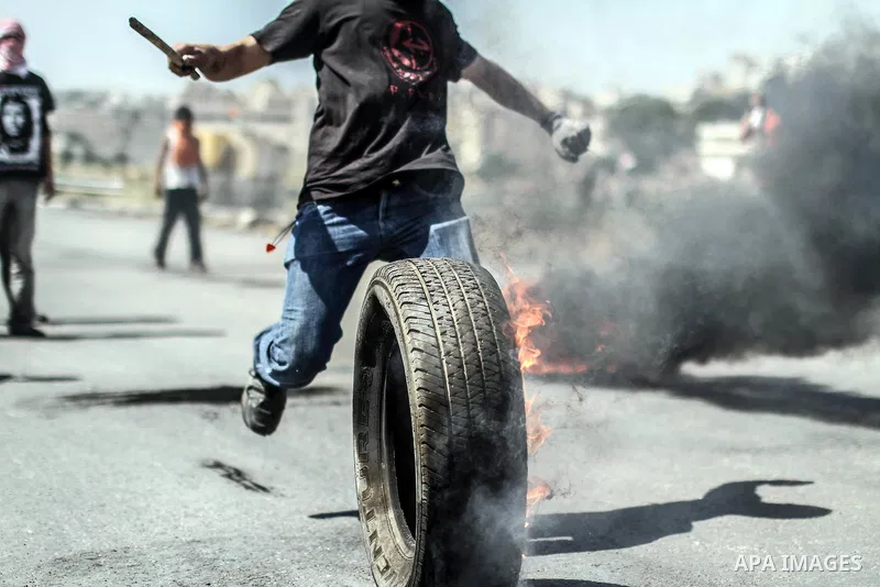 A Palestinian kicks a burning tire toward Israeli police during clashes in front of Ofer prison, near the city of Ramallah, after a demonstration solidarity with prisoners Mahmud Sarsak, prisoners Akram Rikhawi and Samir...