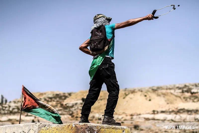 A Palestinian protester throws stones toward Israeli police during clashes in front of Ofer prison, near the city of Ramallah, after a demonstration solidarity with prisoners Mahmud Sarsak, prisoners Akram Rikhawi and Sa...