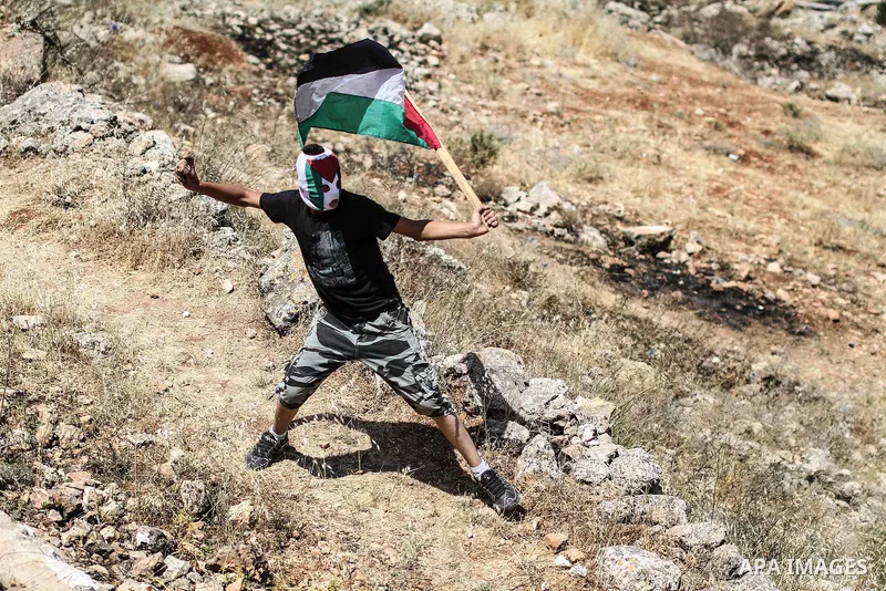 A Palestinian protester throws stones toward Israeli police during clashes in front of Ofer prison, near the city of Ramallah, after a demonstration solidarity with prisoners Mahmud Sarsak, prisoners Akram Rikhawi and Sa...