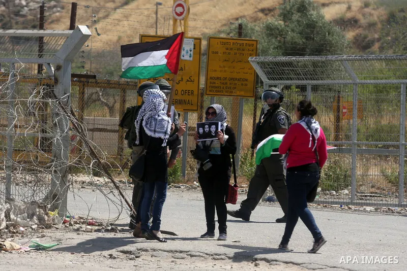Israeli police keep guard as female Palestinian protestors fly their national flag and hold pictures of jailed Palestinian football player Mahmud Sarsak (R) and prisoners Akram Rikhawi (C) and Samir al-Baraka during a de...