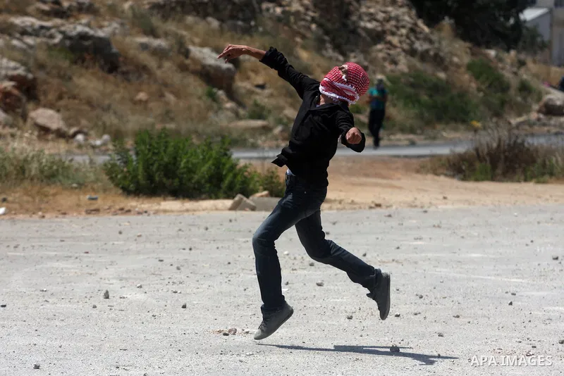 A Palestinian protester throws stones toward Israeli police during clashes in front of Ofer prison, near the city of Ramallah, after a demonstration solidarity with prisoners Mahmud Sarsak, prisoners Akram Rikhawi and Sa...