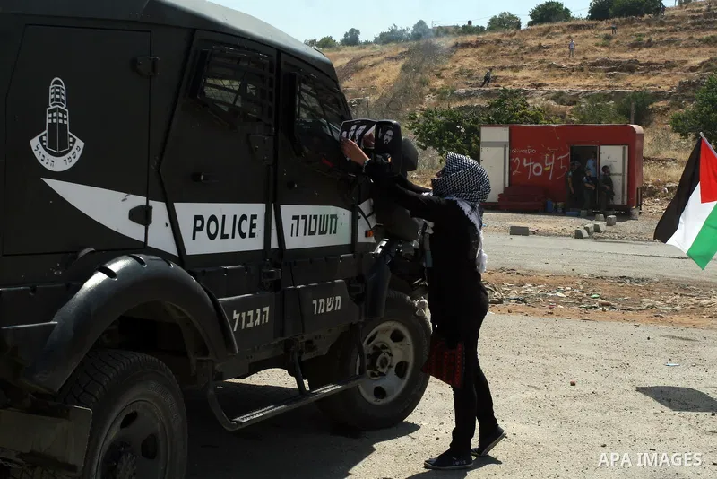 Israeli police keep guard as female Palestinian protestors fly their national flag and hold pictures of jailed Palestinian football player Mahmud Sarsak (R) and prisoners Akram Rikhawi (C) and Samir al-Baraka during a de...