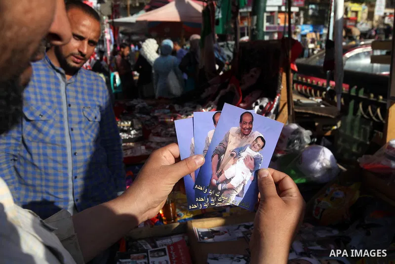 A man show digitally manipulated pictures depicting Egypt's former president Hosni Mubarak and Field Marshal Mohamed Hussein Tantawi, at Tahrir square in Cairo on June 11, 2012. Photo by Majdi Fathi