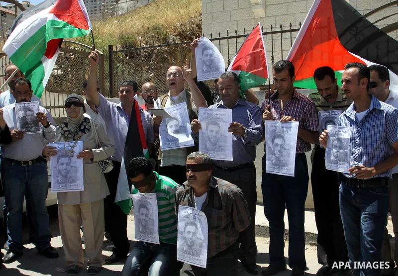 Palestinian protestors hold pictures of Palestinian prisoners Mahmoud Al-Sarsak and Akram al-Rikhawi, whose are still refusing food for 86 days after a deal was made to end a mass prisoner hunger strike, during a demonst...