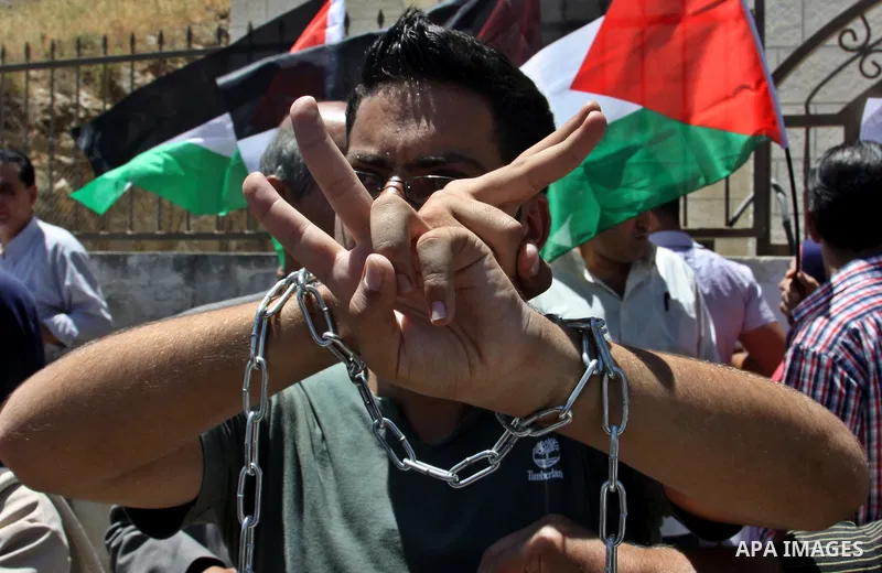 Palestinian protestors hold pictures of Palestinian prisoners Mahmoud Al-Sarsak and Akram al-Rikhawi, whose are still refusing food for 86 days after a deal was made to end a mass prisoner hunger strike, during a demonst...