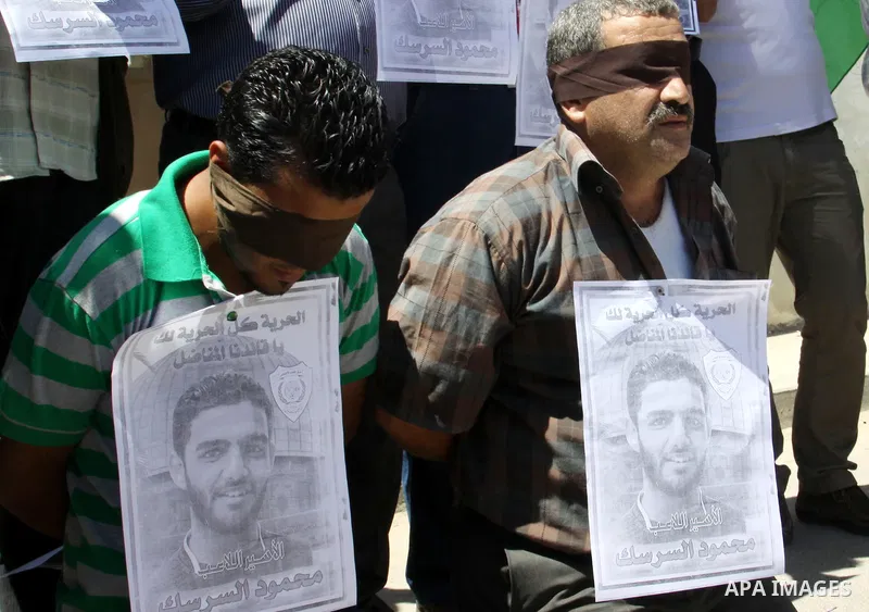 Palestinian protestors hold pictures of Palestinian prisoners Mahmoud Al-Sarsak and Akram al-Rikhawi, whose are still refusing food for 86 days after a deal was made to end a mass prisoner hunger strike, during a demonst...
