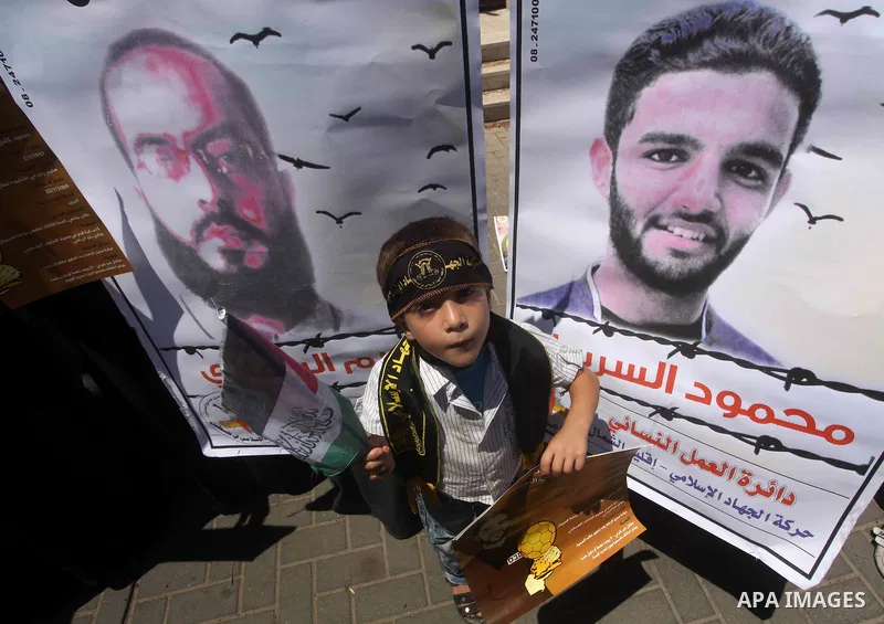 A Palestinian child holds pictures of Palestinian prisoners Mahmoud Al-Sarsak and Akram Al-Rikhawi, whose are still refusing food for 86 days after a deal was made to end a mass prisoner hunger strike, during a demonstra...