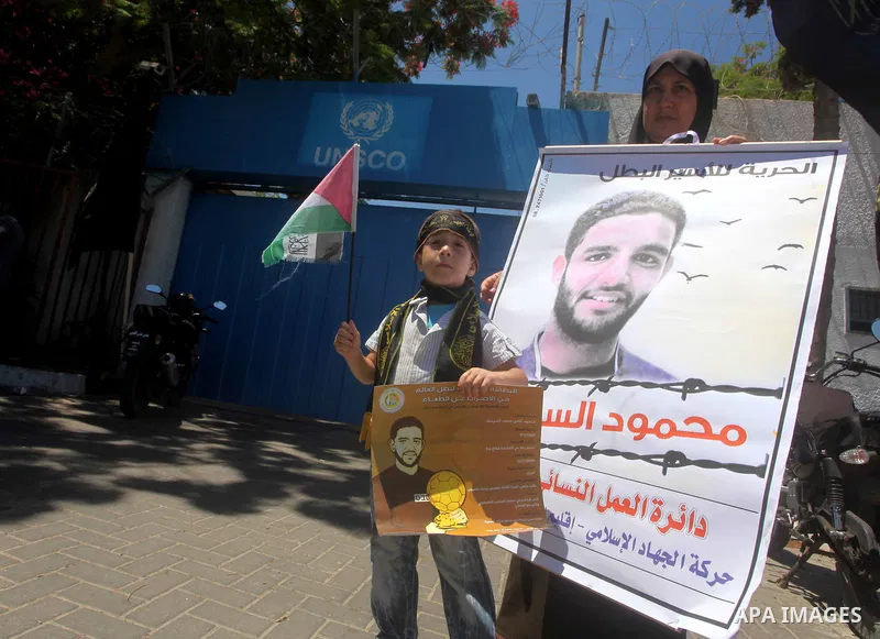 A Palestinian child holds pictures of Palestinian prisoners Mahmoud Al-Sarsak and Akram Al-Rikhawi, whose are still refusing food for 86 days after a deal was made to end a mass prisoner hunger strike, during a demonstra...