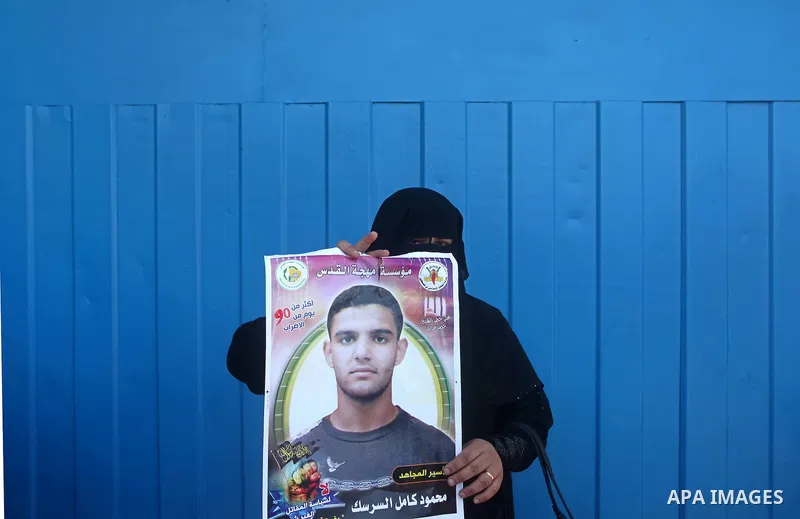 A Palestinian woman holds pictures of Palestinian prisoners Mahmoud Al-Sarsak and Akram Al-Rikhawi, whose are still refusing food for 86 days after a deal was made to end a mass prisoner hunger strike, during a demonstra...