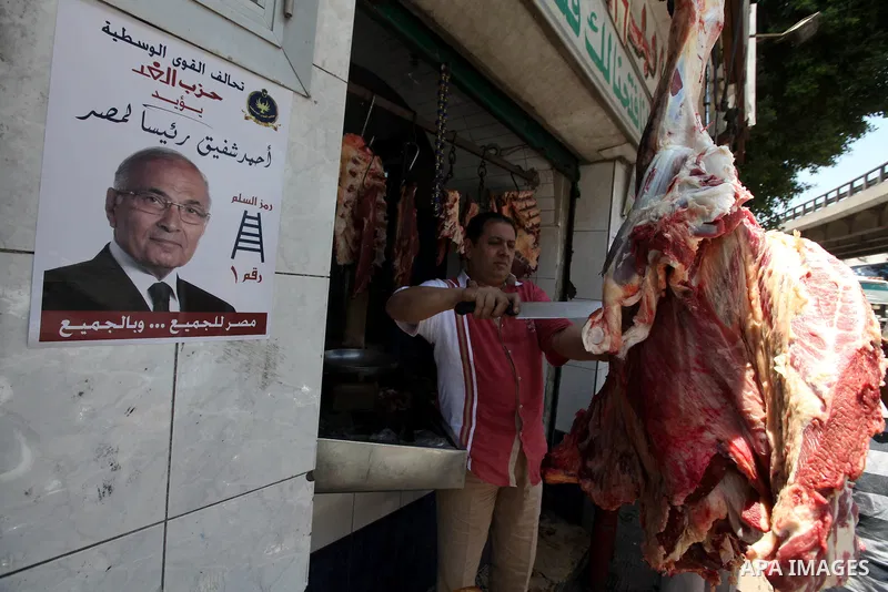 A campaign poster for former Hosni Mubarak's last prime minister Ahmed Shafiq is seen next a butchers in Cairo's al-Sayeda Zenab district on June 12, 2012. A few days before the second round of the historical elections b...