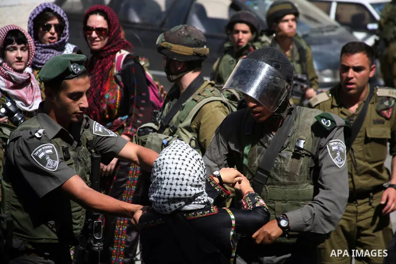 Israeli soldiers and border police try to arrest a demonstrator wearing a traditional Palestinian dress during a demonstration on al-Shuhada street against the closure of the central street in the West Bank town of Hebro...
