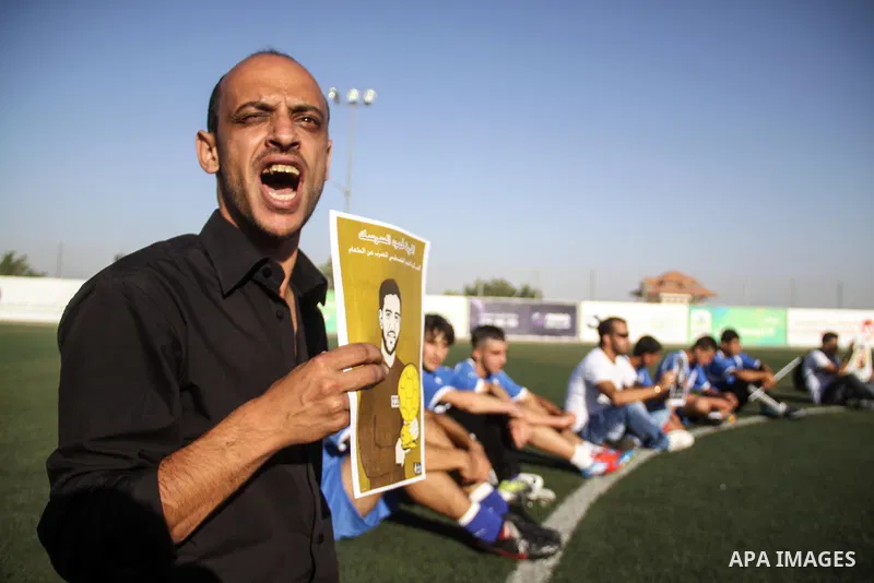 Palestinian athletes hold pictures and banners for prisoner Mahmoud Sarsak, a former player with the Palestinian national football team held in Israeli jails, during a protest calling for release him, at Al-Bireh playgro...