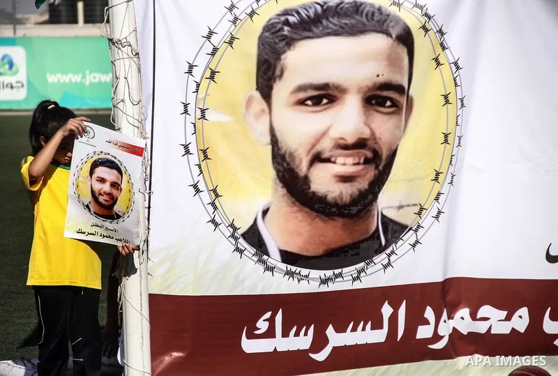 Palestinian athletes hold pictures and banners for prisoner Mahmoud Sarsak, a former player with the Palestinian national football team held in Israeli jails, during a protest calling for release him, at Al-Bireh playgro...