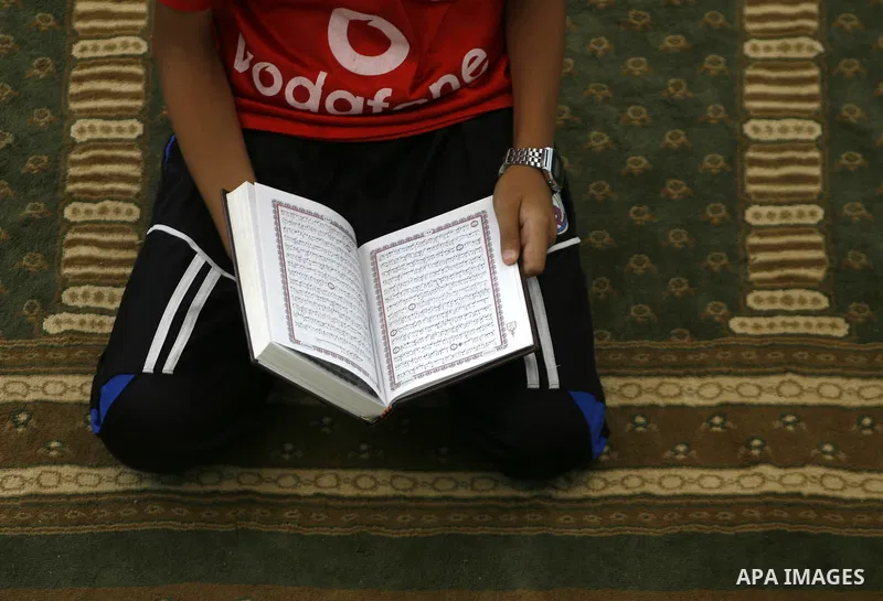 A Palestinian boy reads verses from the Quran during a class on how to read Islam's holy book, at a mosque in Rafah, southern Gaza city, on June 14, 2012. A summer camp in the Gaza Strip, 'Crown of Dignity IV', plans to...