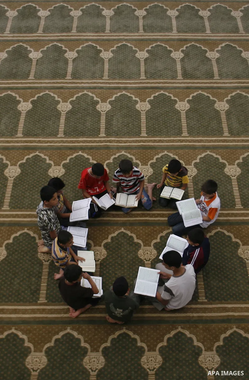 Palestinian boys read verses from the Quran during a class on how to read Islam's holy book, at a mosque in Rafah, southern Gaza city, on June 14, 2012. A summer camp in the Gaza Strip, 'Crown of Dignity IV', plans to te...