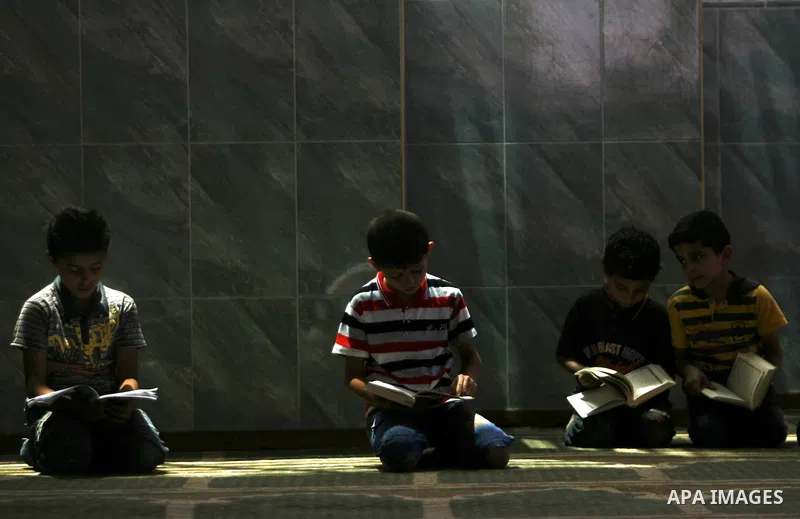 Palestinian boys read verses from the Quran during a class on how to read Islam's holy book, at a mosque in Rafah, southern Gaza city, on June 14, 2012. A summer camp in the Gaza Strip, 'Crown of Dignity IV', plans to te...