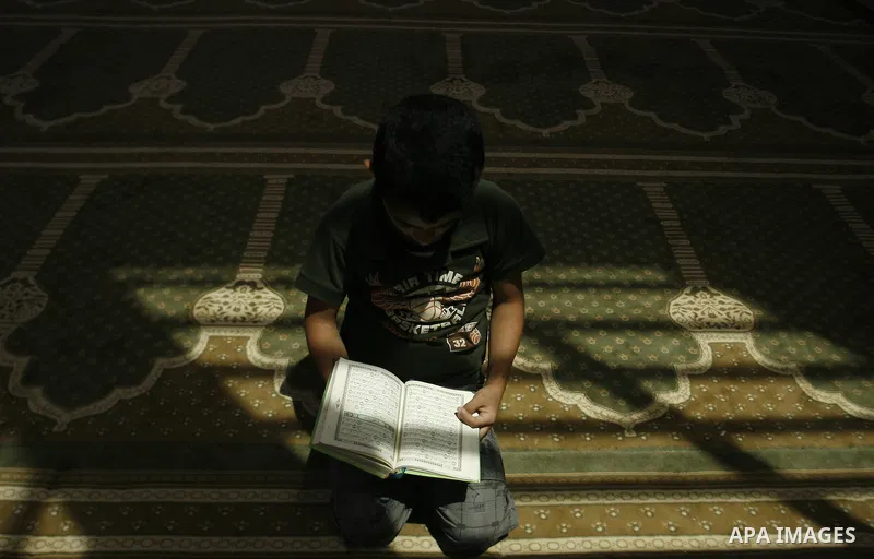 A Palestinian boy reads verses from the Quran during a class on how to read Islam's holy book, at a mosque in Rafah, southern Gaza city, on June 14, 2012. A summer camp in the Gaza Strip, 'Crown of Dignity IV', plans to...