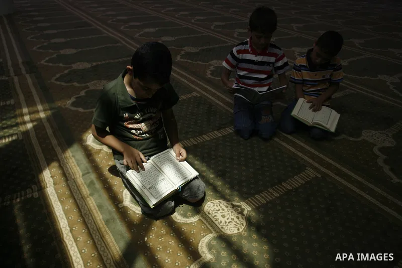 Palestinian boys read verses from the Quran during a class on how to read Islam's holy book, at a mosque in Rafah, southern Gaza city, on June 14, 2012. A summer camp in the Gaza Strip, 'Crown of Dignity IV', plans to te...