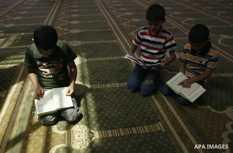 Palestinian boys read verses from the Quran during a class on how to read Islam's holy book, at a mosque in Rafah, southern Gaza city, on June 14, 2012. A summer camp in the Gaza Strip, 'Crown of Dignity IV', plans to te...