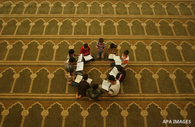 Palestinian boys read verses from the Quran during a class on how to read Islam's holy book, at a mosque in Rafah, southern Gaza city, on June 14, 2012. A summer camp in the Gaza Strip, 'Crown of Dignity IV', plans to te...