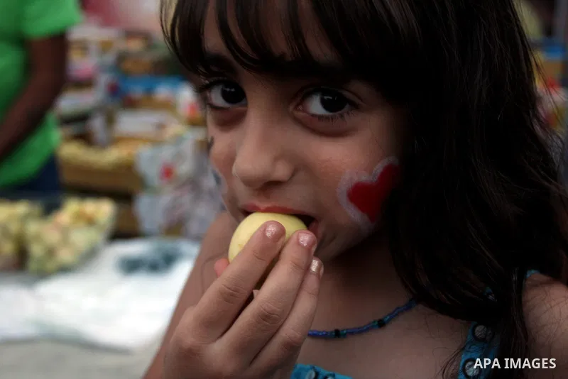 A Palestinian girl takes part in the opening of "Apricot Exhibition" in the village of Jaffna in the West Bank city of Ramallah, Thursday June 14, 2012. Photo by Issam Rimawi