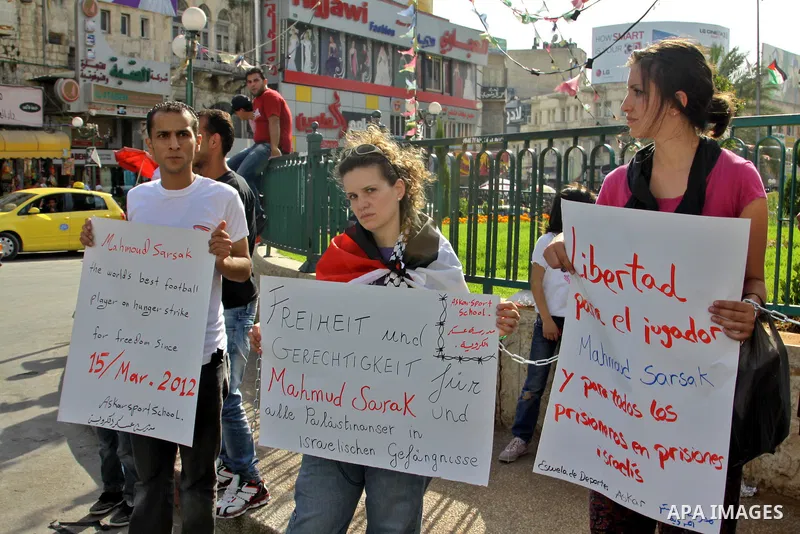 Palestinian protestors hold banners and pictures of Palestinian prisoner Mahmoud Al-Sarsak, who is still refusing food for 92 days after a deal was made to end a mass prisoner hunger strike, during a demonstration in sup...