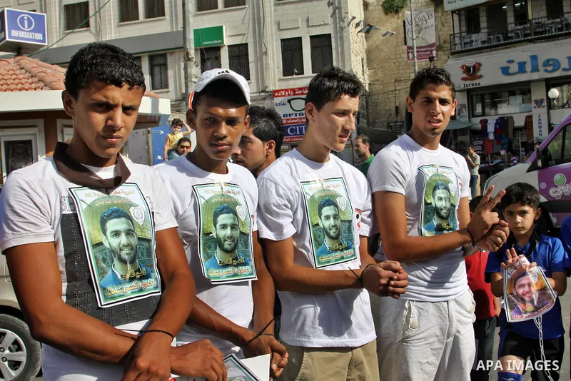 Palestinian protestors hold pictures of Palestinian prisoner Mahmoud Al-Sarsak, who is still refusing food for 92 days after a deal was made to end a mass prisoner hunger strike, during a demonstration in support him, in...