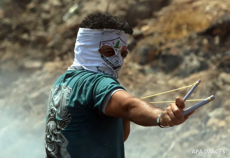A Palestinian protester throws stones at an Israeli soldiers during clashes in the northern West Bank village of Kufr Qaddum, after the weekly protest against the expansion of the nearby Jewish settlement of Kdumim, on M...