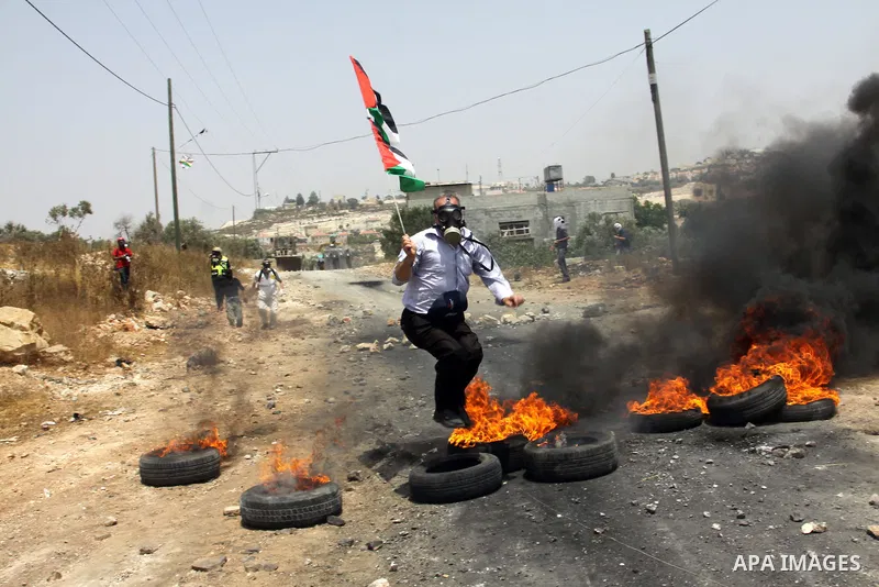 A Palestinian protester throws stones at an Israeli soldiers during clashes in the northern West Bank village of Kufr Qaddum, after the weekly protest against the expansion of the nearby Jewish settlement of Kdumim, on M...