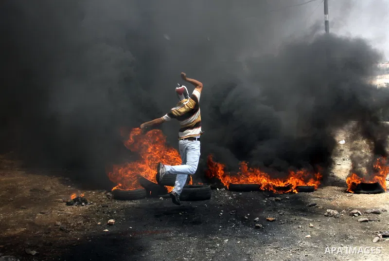 A Palestinian protester throws stones at an Israeli soldiers during clashes in the northern West Bank village of Kufr Qaddum, after the weekly protest against the expansion of the nearby Jewish settlement of Kdumim, on M...