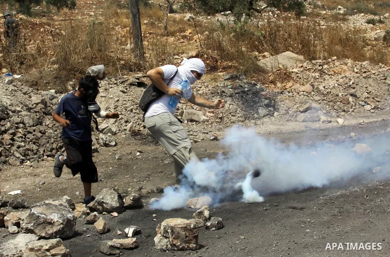 A Palestinian Protester returns a teargas towards Israeli soldiers during clashes in the northern West Bank village of Kufr Qaddum, after the weekly protest against the expansion of the nearby Jewish settlement of Kdumim...