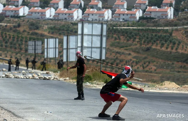 A Palestinian protester throws stones at Israeli soldiers during clashes in the West Bank village of Nabi Saleh, near Ramallah, on June 15, 2012, following a demonstration against the confiscation of Palestinian land to...