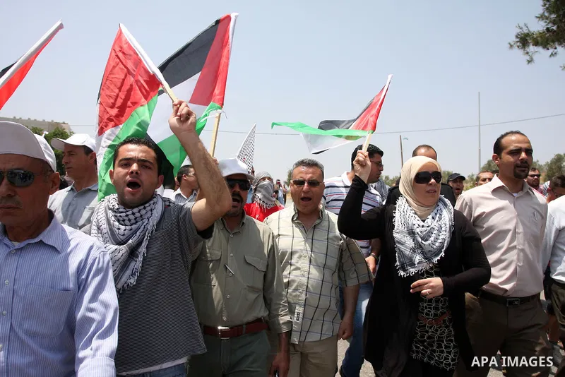Palestinian protesters hold national flags during a demonstration against the confiscation of Palestinian land to expand Jewish settlements, in the West Bank village of Nabi Saleh, near Ramallah, on June 15, 2012. Envoys...
