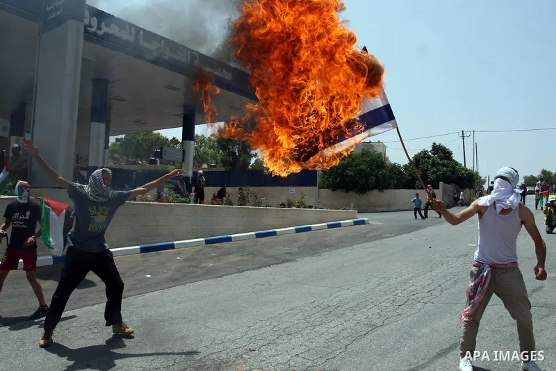 A Palestinian protester burns an Israeli flag during clashes with Israeli soldiers in the West Bank village of Nabi Saleh, near Ramallah, on June 15, 2012, following a demonstration against the confiscation of Palestinia...