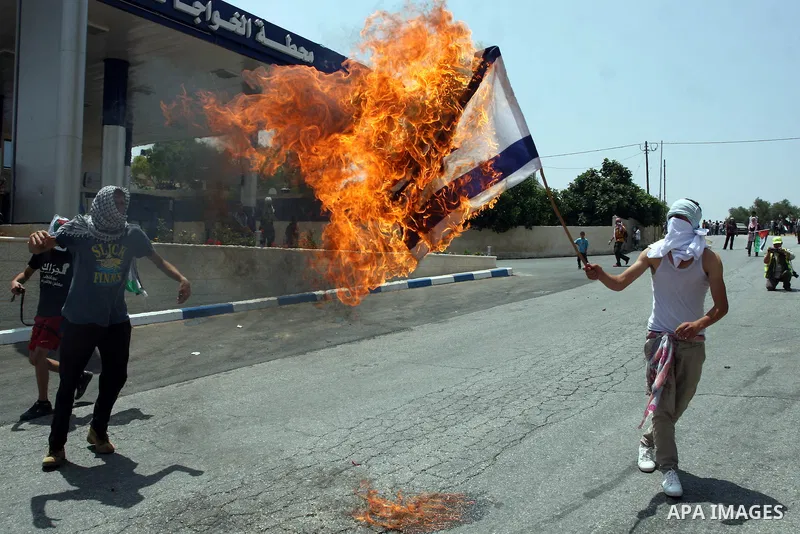 A Palestinian protester burns an Israeli flag during clashes with Israeli soldiers in the West Bank village of Nabi Saleh, near Ramallah, on June 15, 2012, following a demonstration against the confiscation of Palestinia...