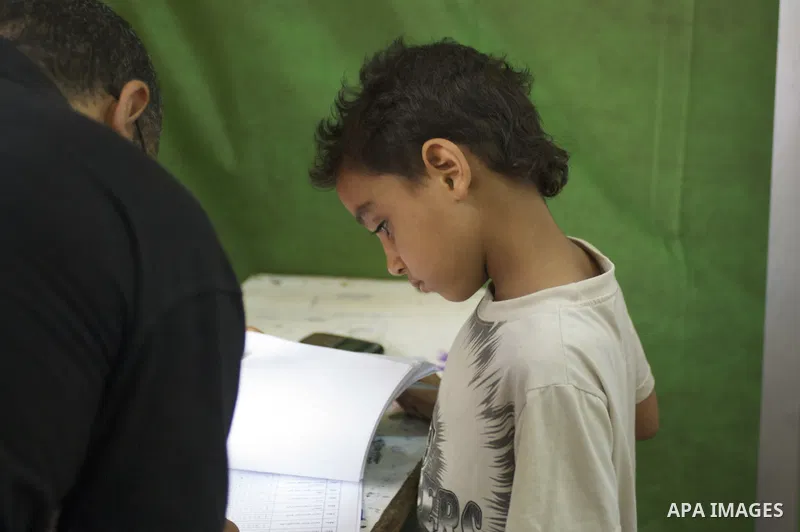June 16, 2012 - Cairo, Egypt - An Egyptian boy watches as his father signs the voter roll on the first day of the presidential run-off electons in Cairo on Saturday, June 16, 2012. Egyptians had the choice between Muhamm...
