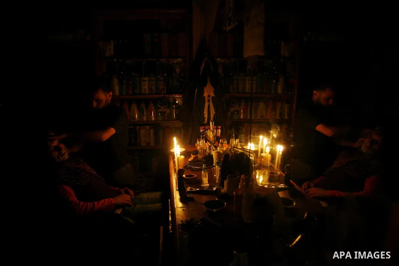 A Palestinian barber cuts hair for youths and lighting a candle during a power outage in a barber shop in Rafah, southern Gaza Strip on June 16, 2012. Photo by Eyad Al Baba