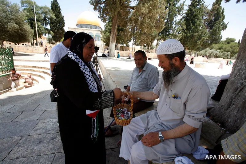 A Muslim woman gives candy during a celebration of the Islamic holiday of Isra Mi'raj in the Al-Aqsa mosque, in the Jerusalem old city, on June 17, 2012. The holiday marks what Muslims believe is Prophet Mohammad's journ...